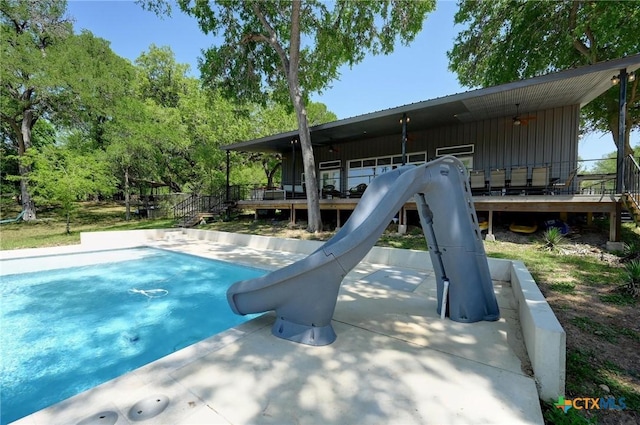 outdoor pool featuring a water slide and a deck