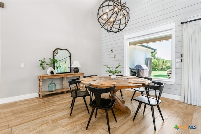 dining area featuring a chandelier, wooden walls, and light hardwood / wood-style flooring