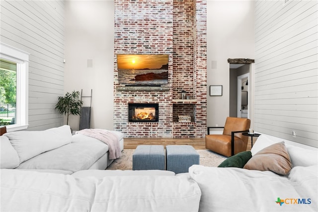 living room featuring a fireplace, a high ceiling, and light hardwood / wood-style floors