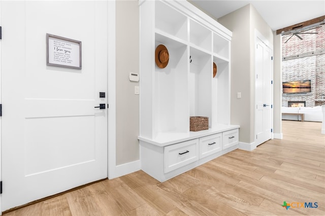 mudroom with a stone fireplace and light hardwood / wood-style floors