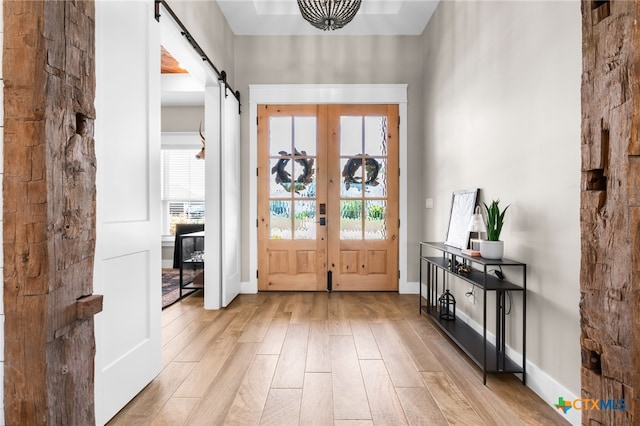 foyer with a barn door, light hardwood / wood-style floors, and french doors