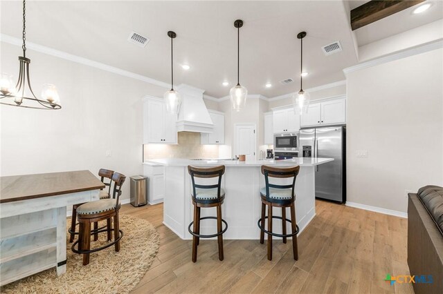 8917 Sassafras St, Temple, TX 76502 - kitchen with appliances with stainless steel finishes, custom exhaust hood, light wood finished floors, a kitchen bar, and white cabinets