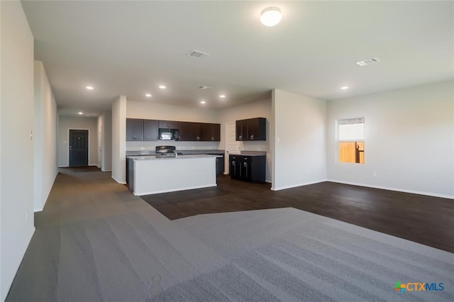 kitchen with dark brown cabinets, dark hardwood / wood-style floors, and a center island with sink