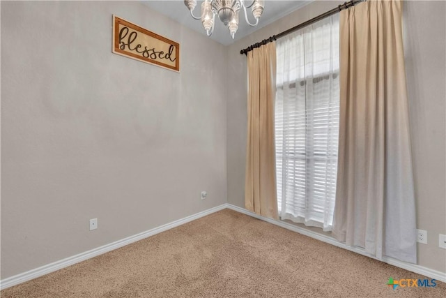 empty room with baseboards, carpet flooring, and a notable chandelier