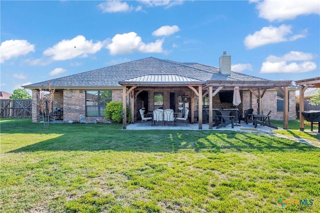 rear view of property with a patio area, a chimney, fence, a yard, and brick siding