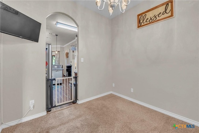 unfurnished room featuring arched walkways, baseboards, carpet, and an inviting chandelier