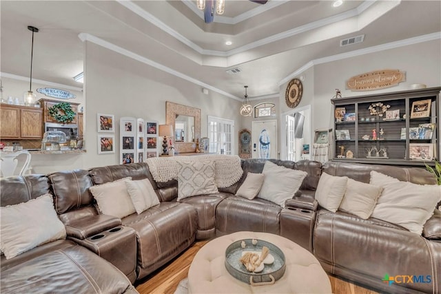 living area featuring a raised ceiling, visible vents, a ceiling fan, and ornamental molding
