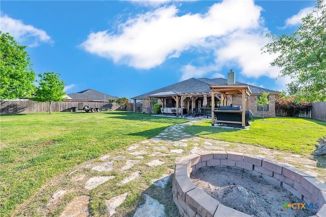 rear view of property with a fenced backyard, a yard, a patio, an outdoor fire pit, and a gazebo