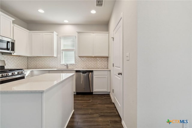 310 Spiny Lizard Ln, San Marcos, TX 78666 - kitchen with appliances with stainless steel finishes, backsplash, dark wood-type flooring, white cabinetry, and recessed lighting
