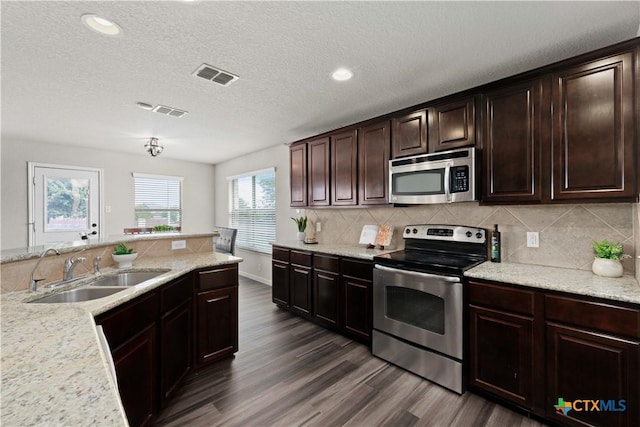 kitchen with a textured ceiling, sink, stainless steel appliances, and dark wood-type flooring