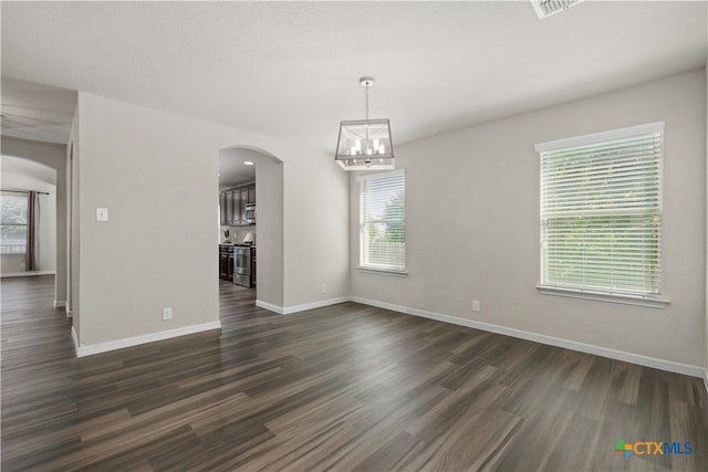 empty room with a chandelier and dark wood-type flooring