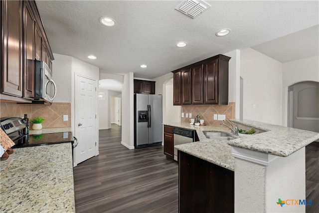 kitchen with sink, dark hardwood / wood-style floors, backsplash, kitchen peninsula, and appliances with stainless steel finishes