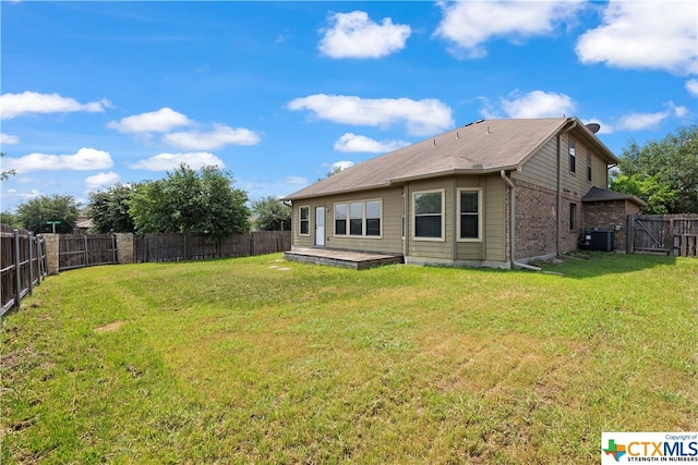 back of property with a lawn and central AC