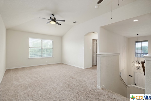 unfurnished room with a wealth of natural light, light colored carpet, and ceiling fan with notable chandelier