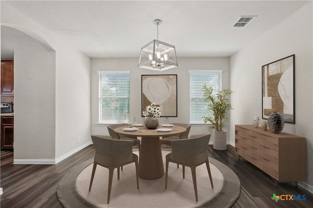 dining area featuring a textured ceiling, dark hardwood / wood-style flooring, a healthy amount of sunlight, and a notable chandelier