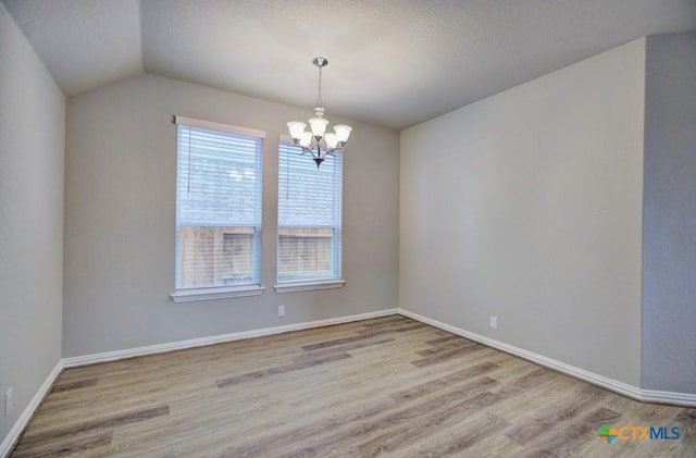 unfurnished room featuring light hardwood / wood-style floors, vaulted ceiling, and a notable chandelier