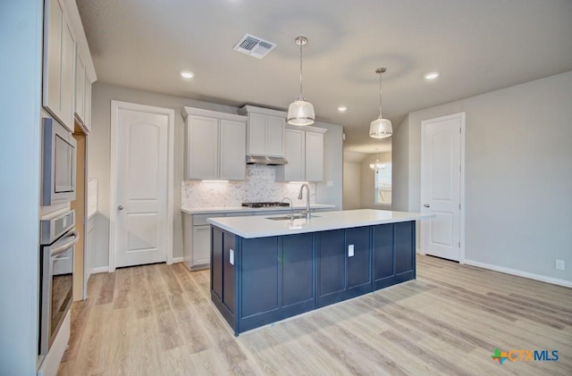 kitchen featuring white cabinetry, sink, a kitchen island with sink, and light hardwood / wood-style flooring