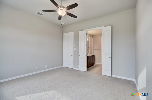 unfurnished bedroom with ceiling fan, light colored carpet, and ensuite bath