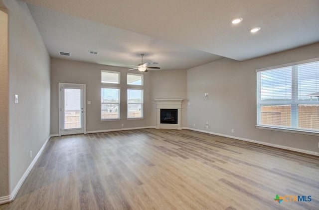 unfurnished living room featuring ceiling fan, plenty of natural light, and light hardwood / wood-style flooring