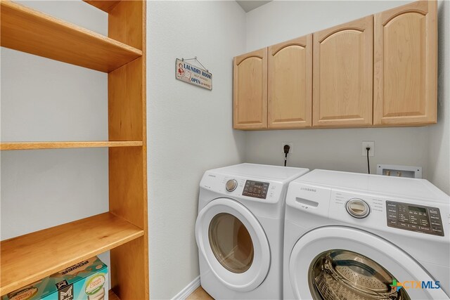 laundry room with washing machine and dryer and cabinets