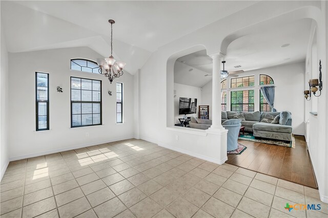 interior space featuring lofted ceiling, ceiling fan with notable chandelier, ornate columns, and light hardwood / wood-style flooring