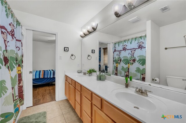 bathroom with toilet, vanity, and tile patterned floors