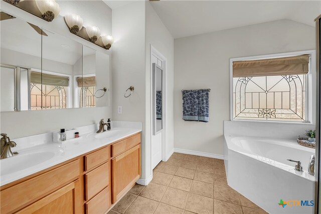 bathroom featuring a bath, tile patterned floors, vanity, and vaulted ceiling