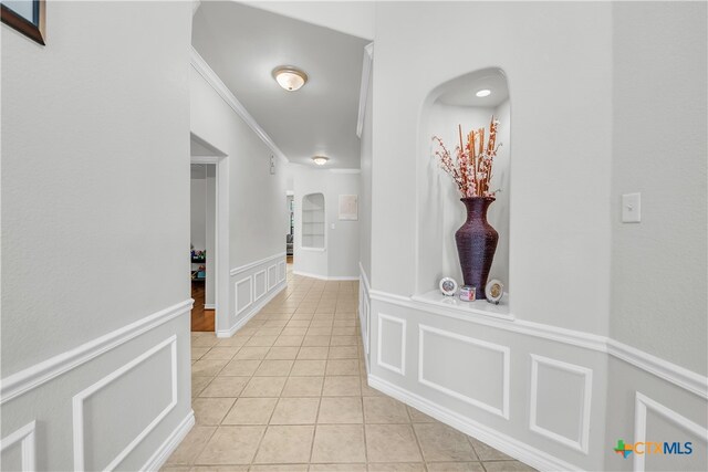 hallway with light tile patterned flooring and crown molding