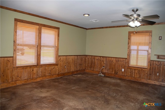 203 S Gisler St, Austwell, TX 77950 - spare room featuring crown molding, a wealth of natural light, ceiling fan, and wood walls