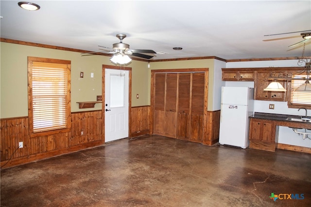 203 S Gisler St, Austwell, TX 77950 - kitchen featuring white refrigerator, ceiling fan, sink, and wooden walls