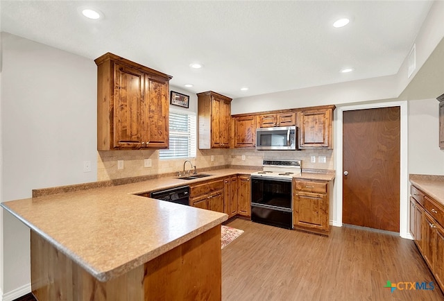 kitchen featuring white range with electric cooktop, sink, light hardwood / wood-style floors, dishwasher, and kitchen peninsula