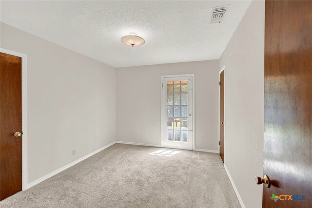 unfurnished room with a textured ceiling and light carpet