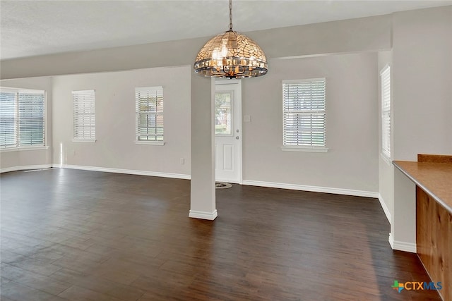 empty room with dark wood-type flooring, a chandelier, and a healthy amount of sunlight