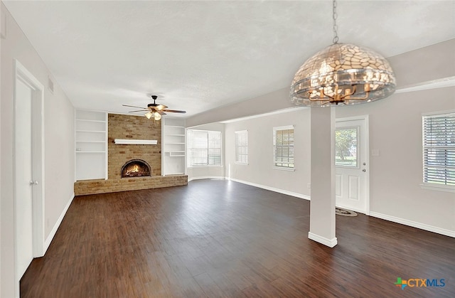 unfurnished living room with dark hardwood / wood-style flooring, ceiling fan, a brick fireplace, and built in shelves