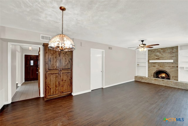 unfurnished living room featuring dark hardwood / wood-style floors, a textured ceiling, ceiling fan, a fireplace, and built in features