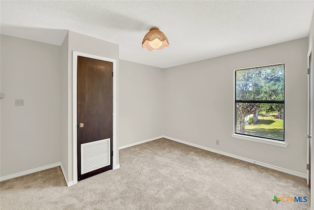 carpeted empty room with a textured ceiling