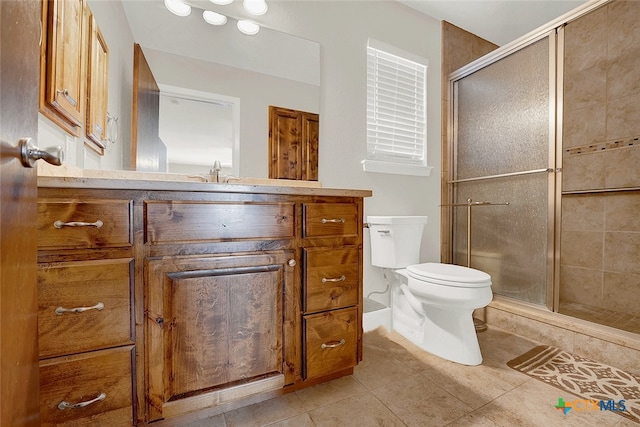 bathroom featuring toilet, vanity, tile patterned flooring, and a shower with shower door