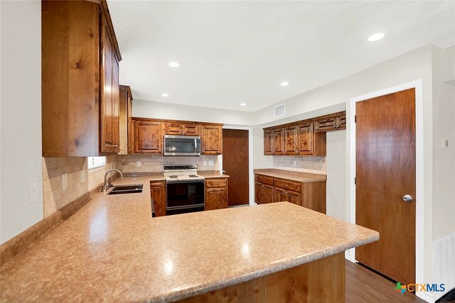 kitchen featuring wood-type flooring, sink, kitchen peninsula, and electric stove