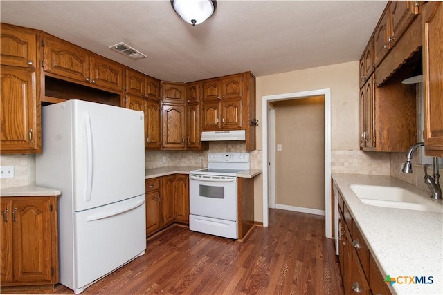 1401 N Penelope St, Belton, TX 76513 - kitchen featuring white appliances, under cabinet range hood, brown cabinetry, and tasteful backsplash