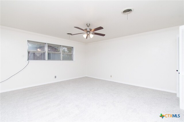 carpeted spare room with ceiling fan and crown molding