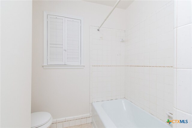 bathroom featuring toilet and tiled shower / bath