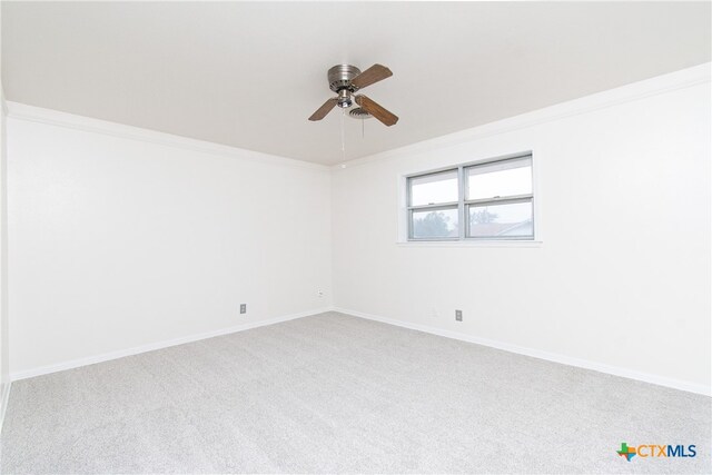 carpeted spare room featuring ceiling fan and crown molding