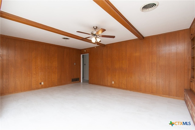 unfurnished room featuring beamed ceiling, wood walls, and ceiling fan