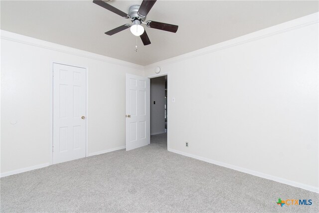 carpeted spare room featuring ceiling fan and crown molding