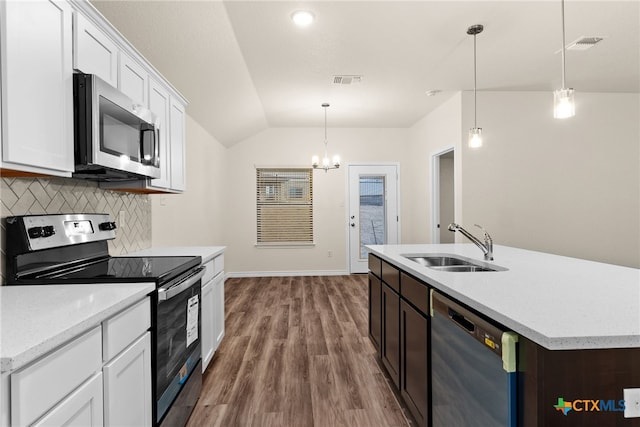 kitchen featuring stainless steel appliances, vaulted ceiling, sink, pendant lighting, and white cabinetry