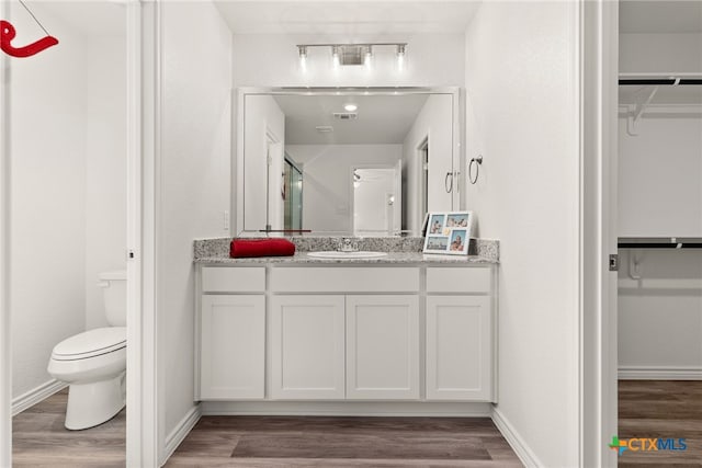 bathroom with toilet, hardwood / wood-style flooring, and vanity