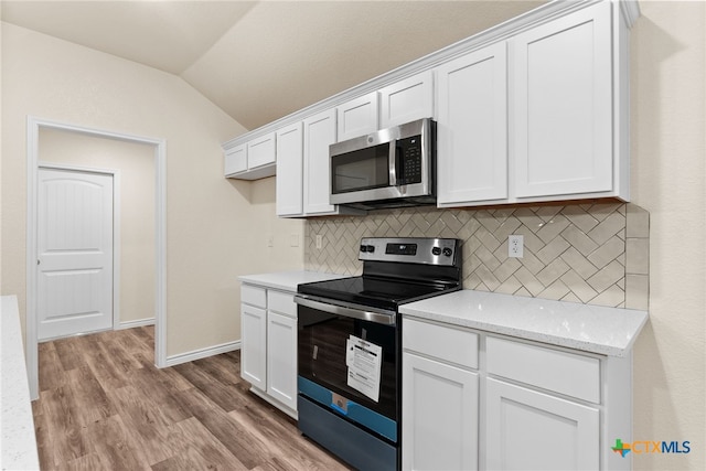 kitchen with light hardwood / wood-style flooring, vaulted ceiling, decorative backsplash, white cabinetry, and stainless steel appliances