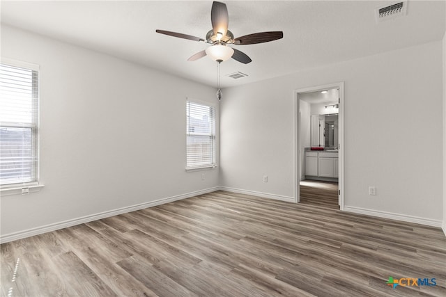 unfurnished bedroom with ceiling fan, hardwood / wood-style flooring, and connected bathroom