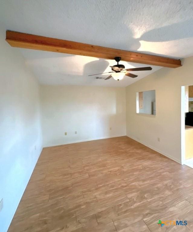 empty room featuring lofted ceiling with beams, a textured ceiling, ceiling fan, and light hardwood / wood-style flooring