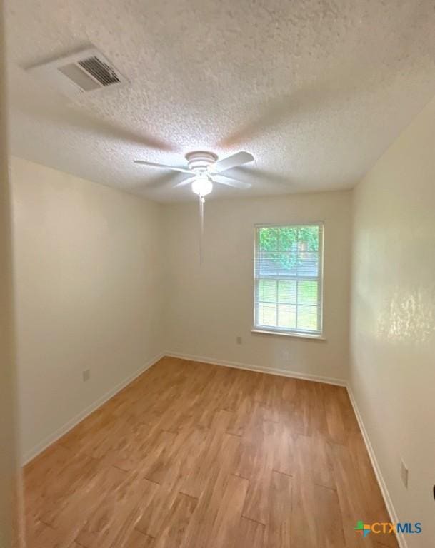 spare room featuring ceiling fan, a textured ceiling, and light wood-type flooring